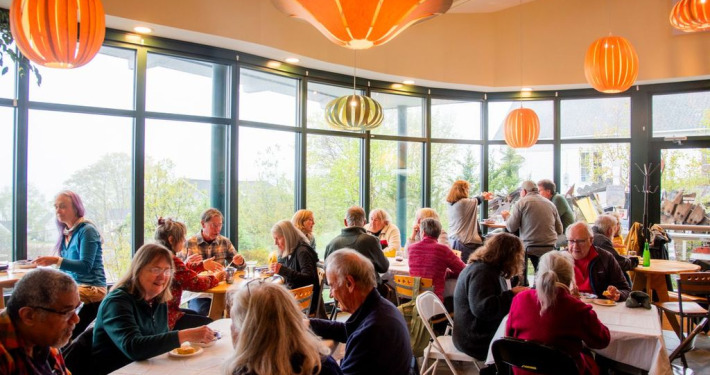 People gathered talking and laughing around warmly lit tables at the Stonington Opera House during the 2025 Wings, Waves and Woods Festival.